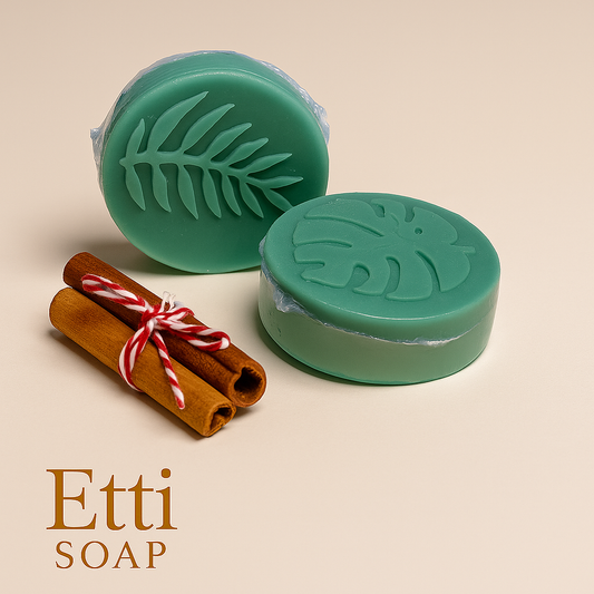 Two green soaps with leaf designs and two cinnamon sticks on a beige background, featuring the brand 'Etti Soap'.