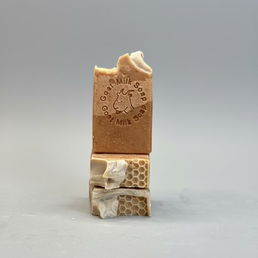 Stack of goat milk soap bars with honeycomb design on a blurred background