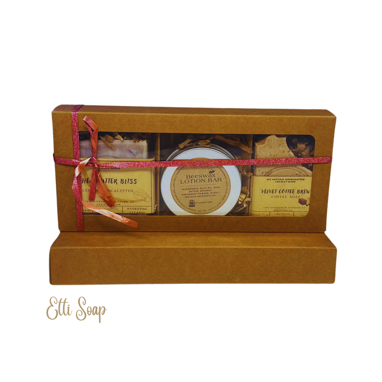 Etti Soap Winter Joy Gift Box featuring Shea Butter Bliss Soap, Velvet Coffee Brew Soap, and Beeswax Lotion Bar in a kraft box with a pink ribbon.