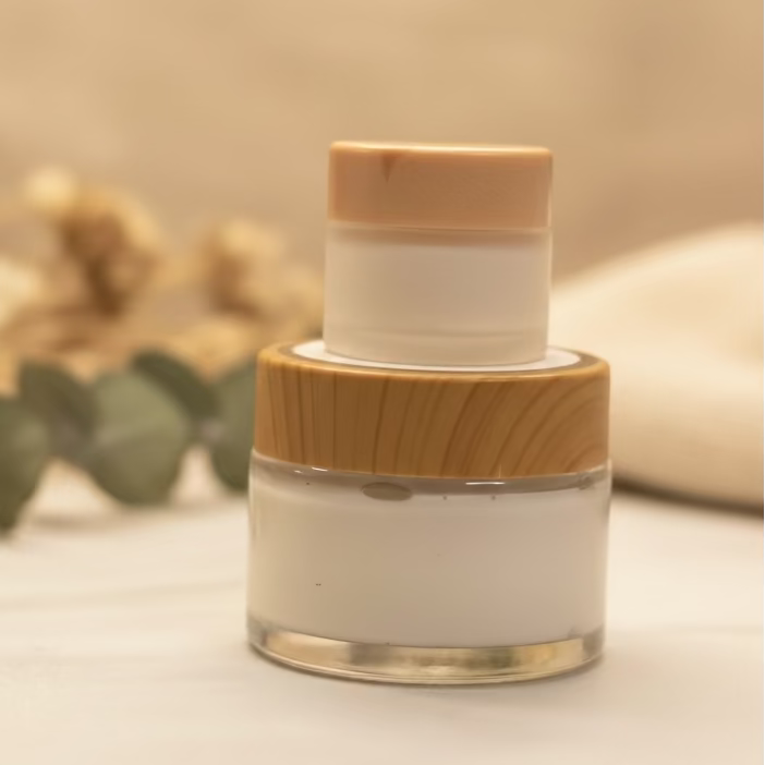 Two white jars with brown lids on a beige surface with blurred greenery in the background