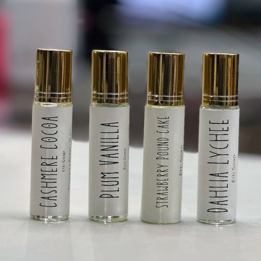 Four small perfume bottles with gold caps on a light surface.