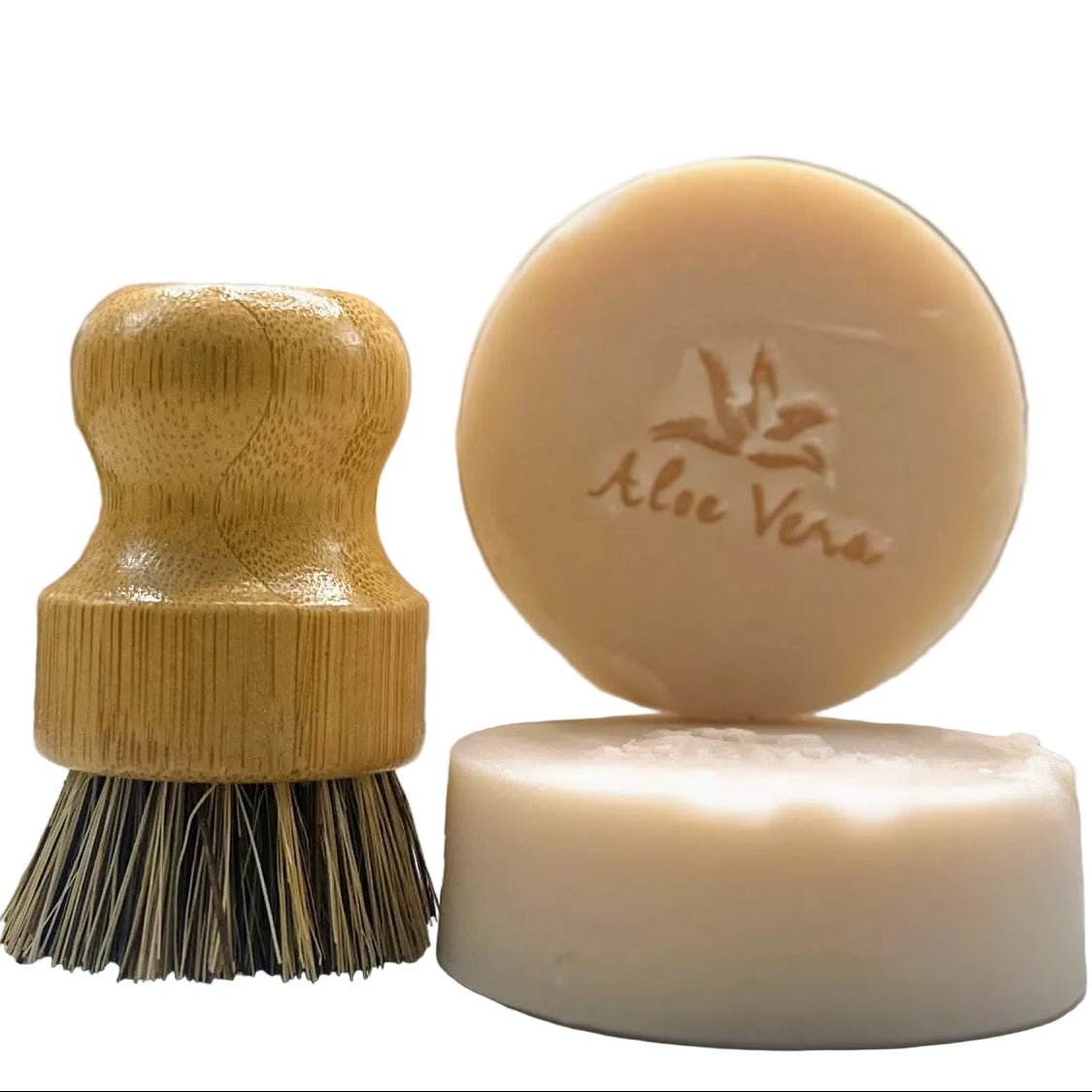 Bamboo brush and two bars of soap with 'Aloe Vera' branding on a blurred background