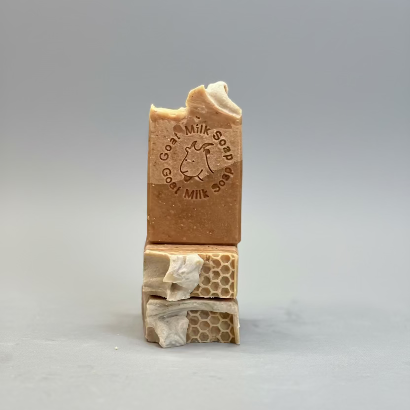 Stack of goat milk soap bars with honeycomb design on a blurred background