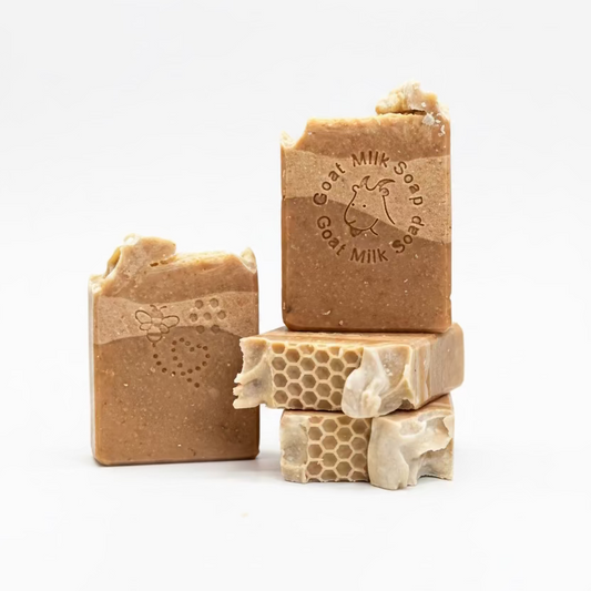 Three bars of goat milk soap with visible branding on a neutral background