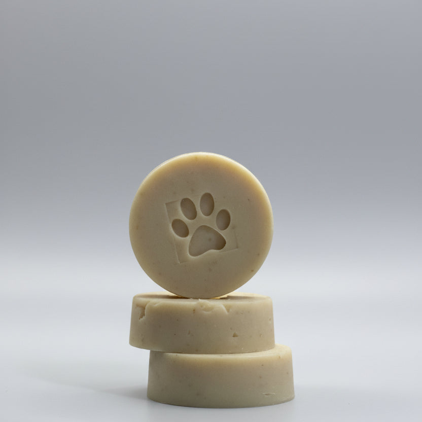 Three cylindrical dog treats with a paw print design stacked on a surface.