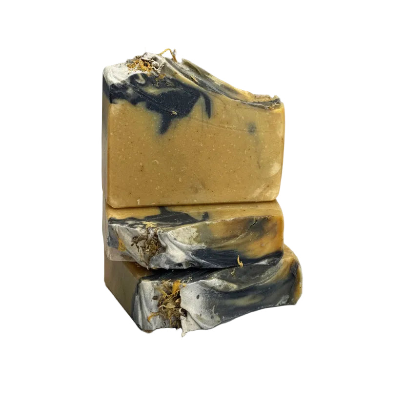 Three layered soap bar with natural elements on a light surface