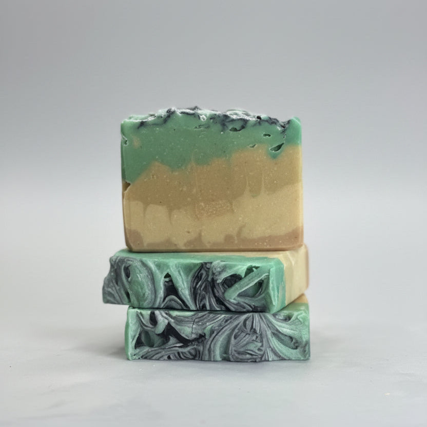 Three bars of soap with green and beige marbled pattern on a white surface.