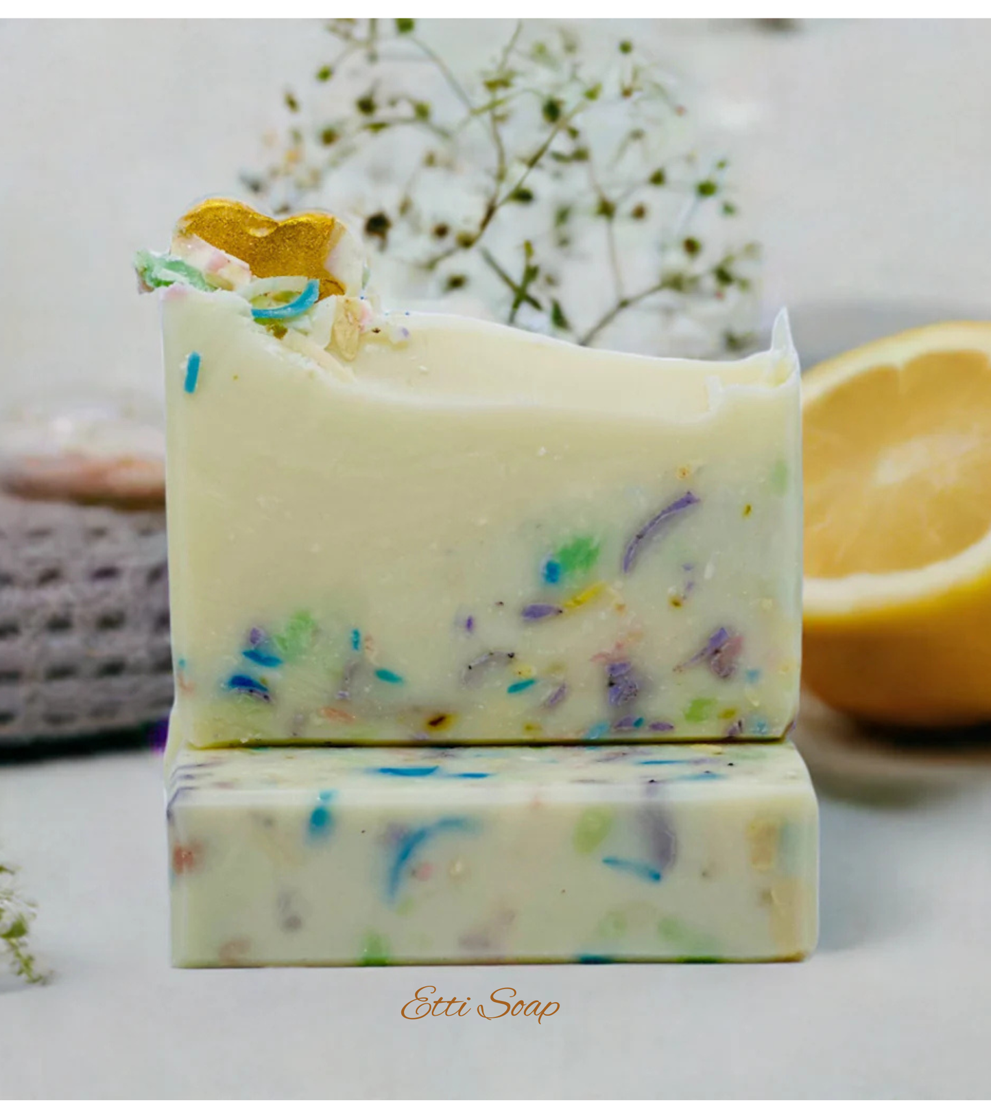 Etti Soap artisan soap with rainbow specks and golden heart decoration, photographed under soft white lighting on a white backdrop.