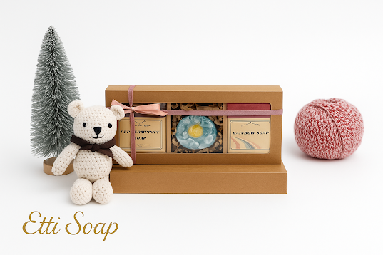Etti Soap holiday gift box with Purple Serenity and Rainbow soaps and daisy round soap, styled with tree and toy bear.